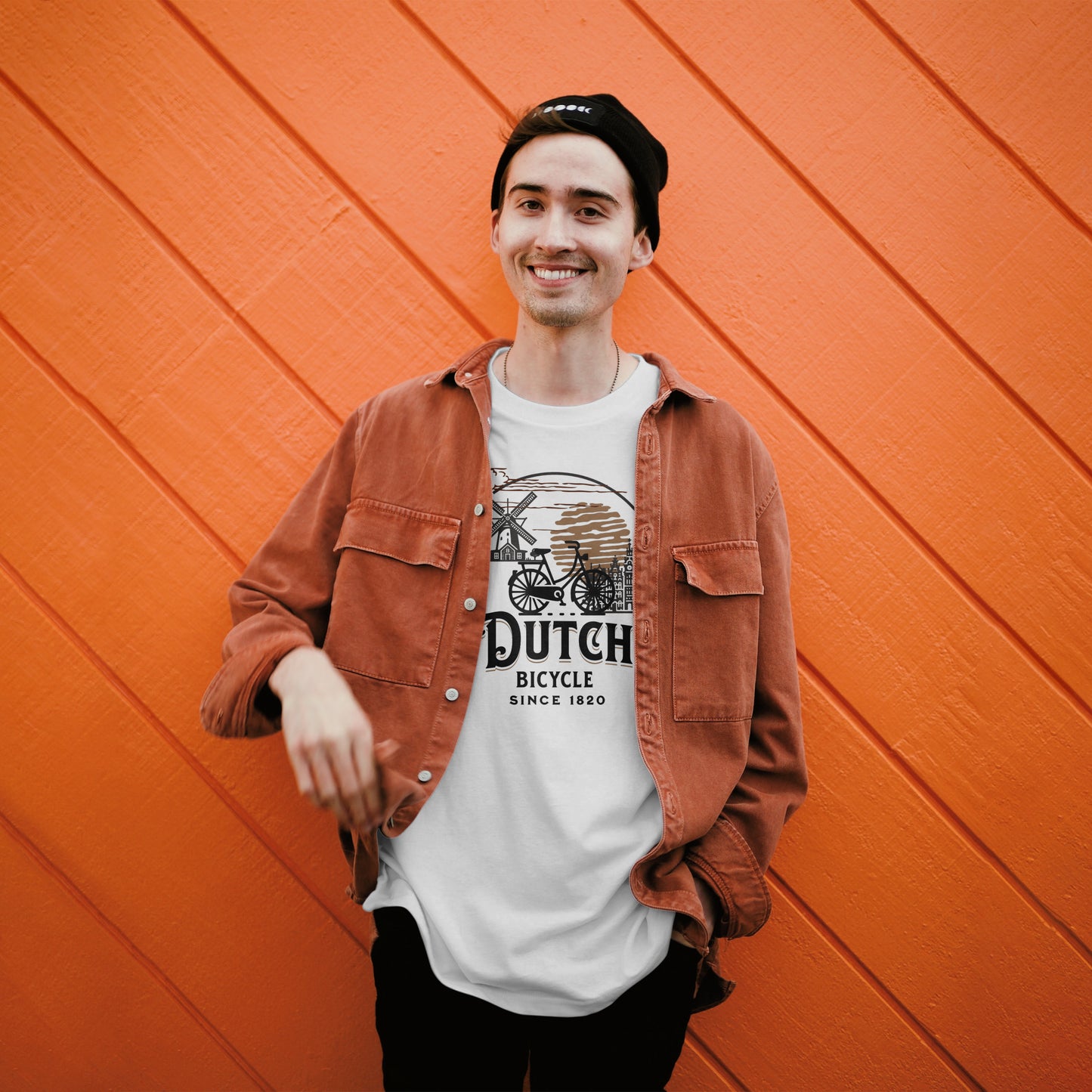 Lachende man voor oranje muur draagt Dutch Bicycle T-shirt met open overhemd
